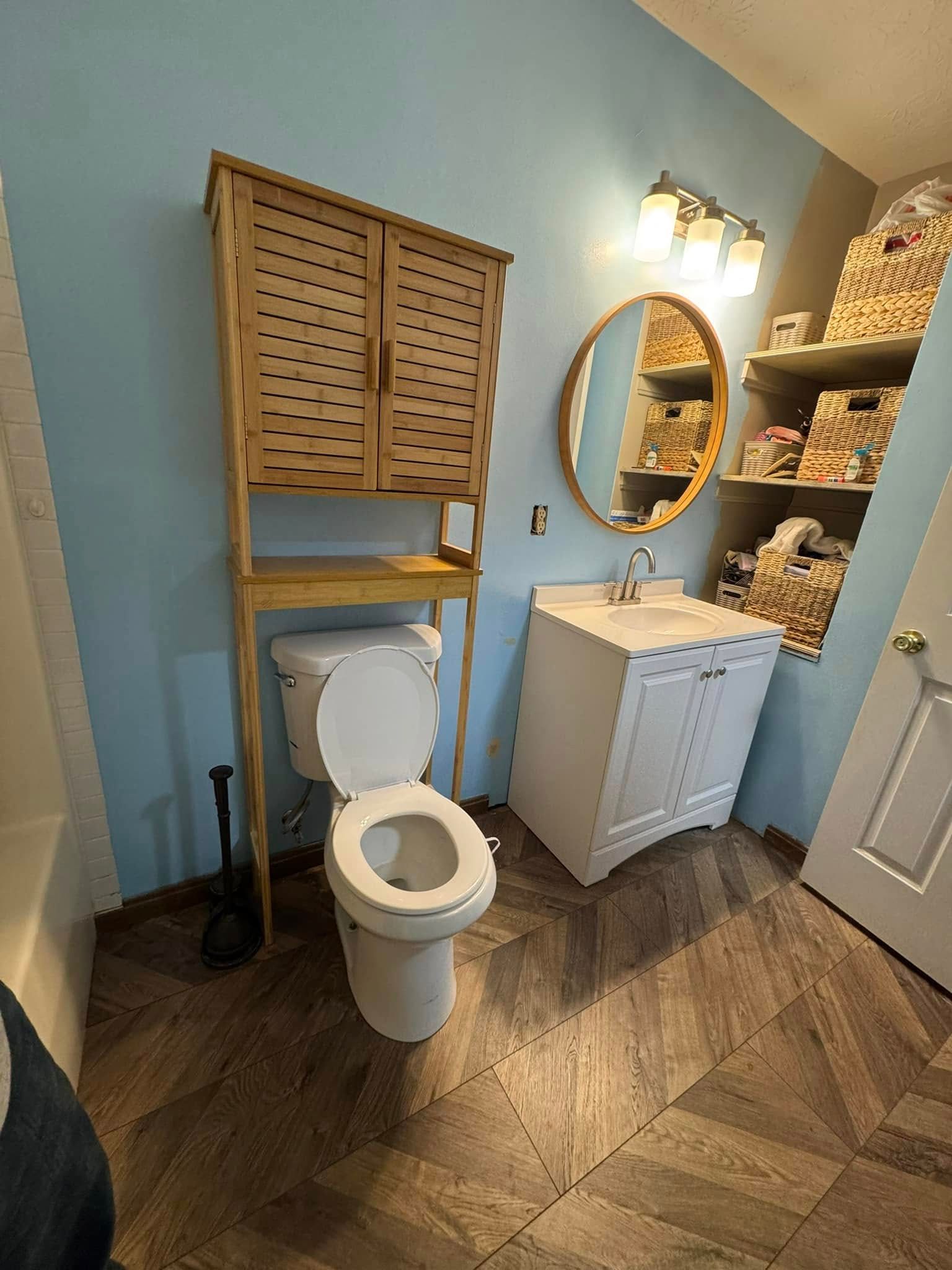 A bathroom with a toilet , sink and mirror.