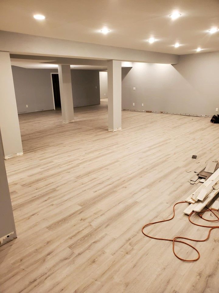 A large empty room with a wooden floor and a power cord.