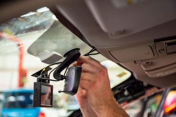 A man is installing a rear view mirror in a car.
