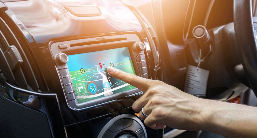 A person is pointing at a map on a car dashboard.