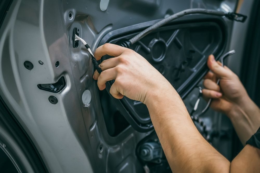 A person is fixing a car door with a screwdriver.