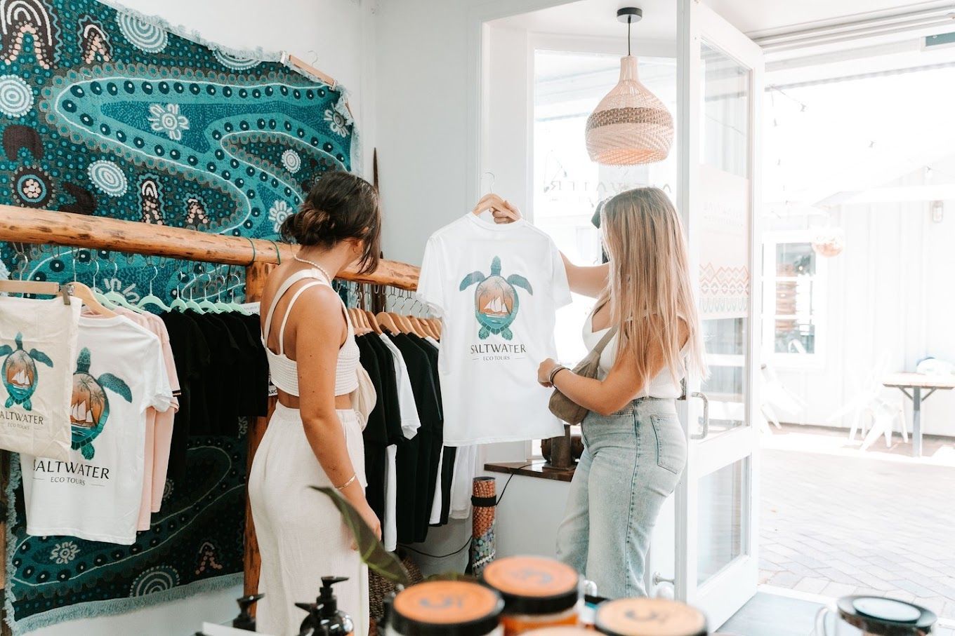 Two women are looking at a t-shirt in a store.