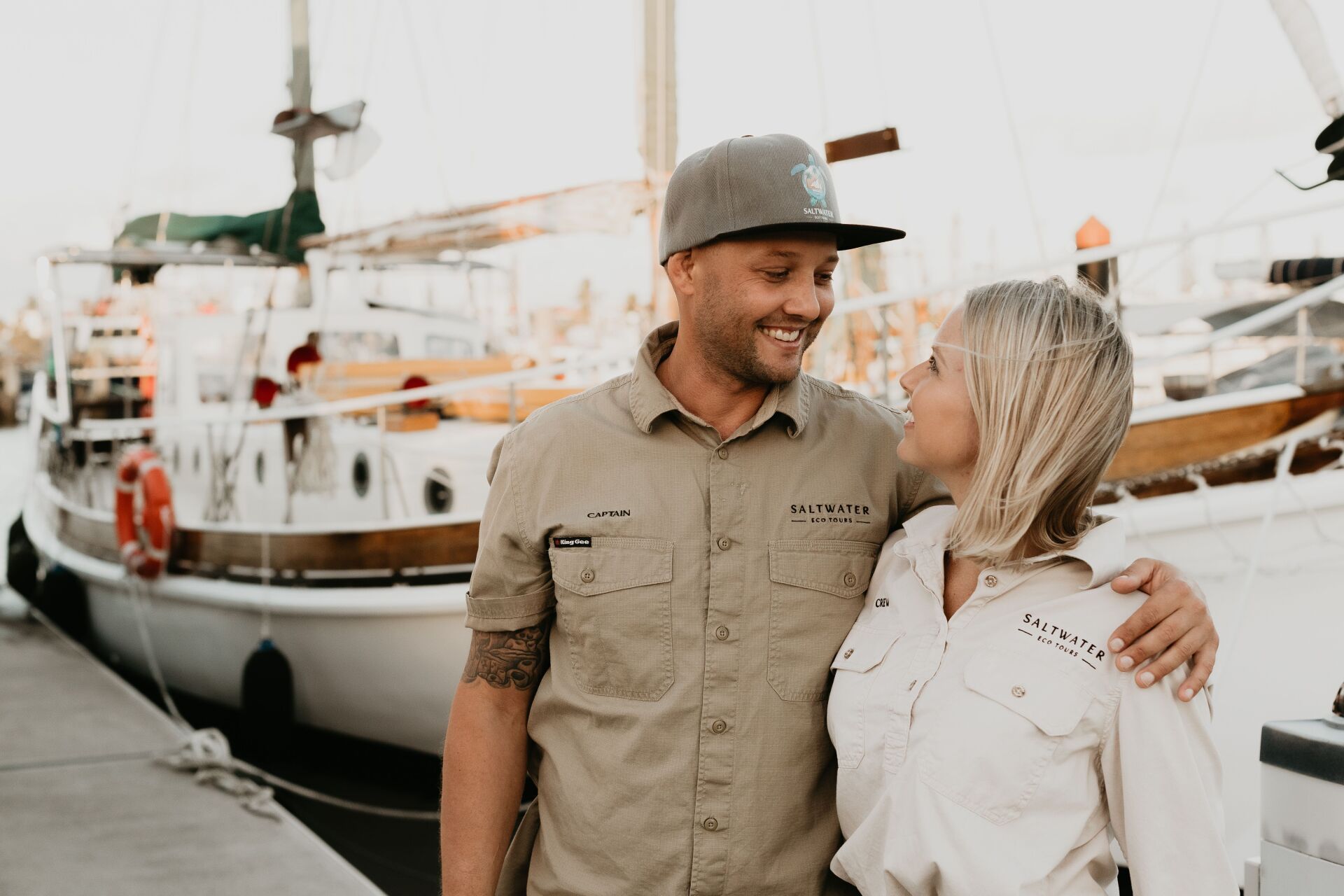 A man and a woman are standing next to each other in front of a boat.