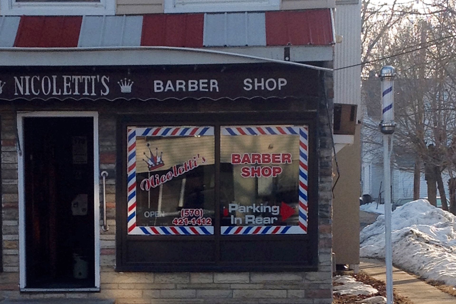 A barber shop with a red white and blue awning