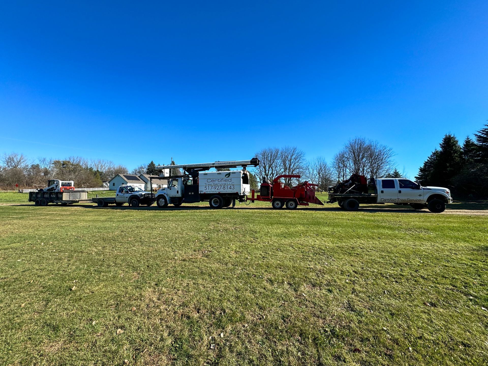 Several trucks and machinery parked on a grassy field on a sunny day.