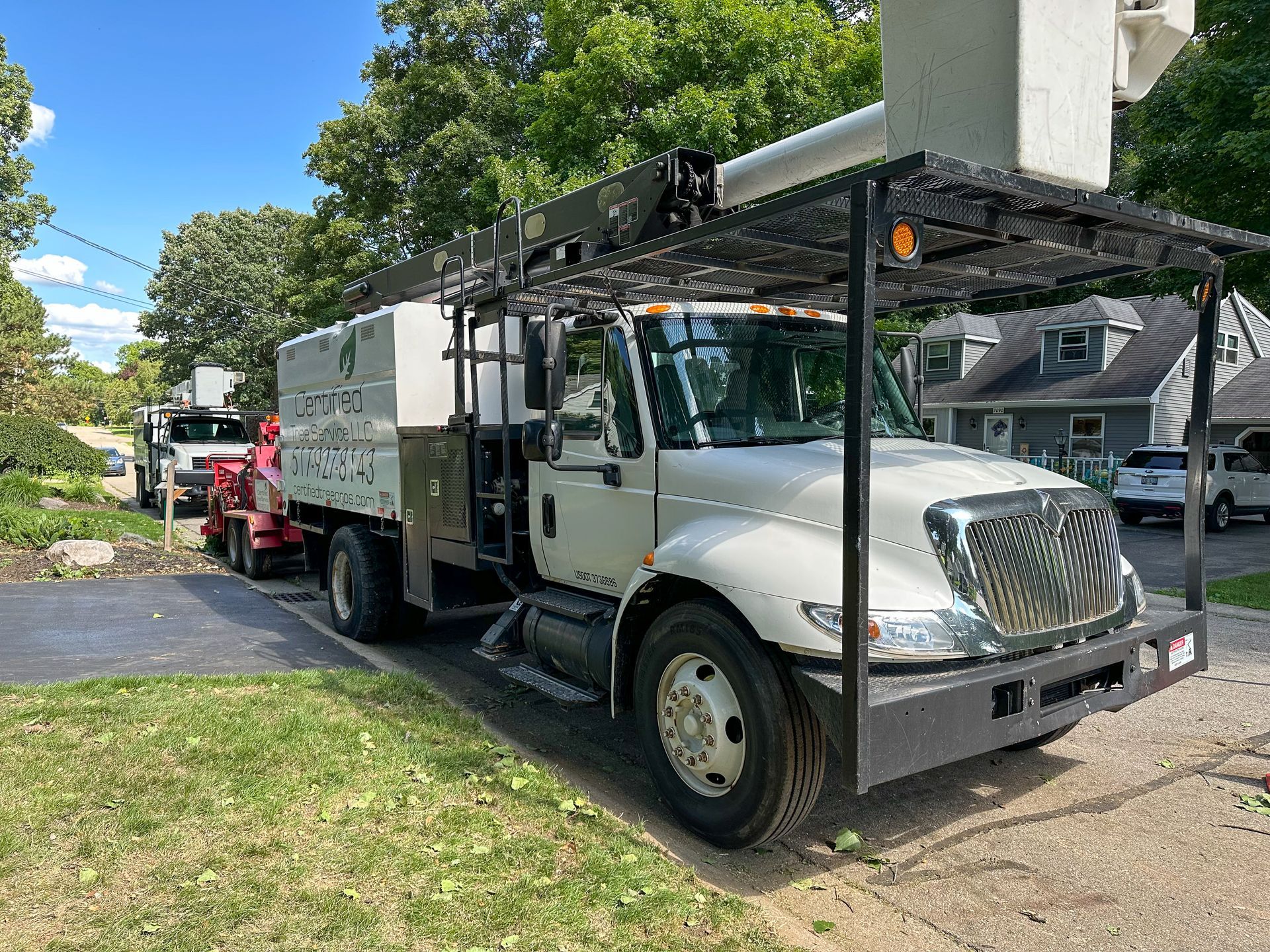 A yellow tractor is carrying a pile of branches in the snow.