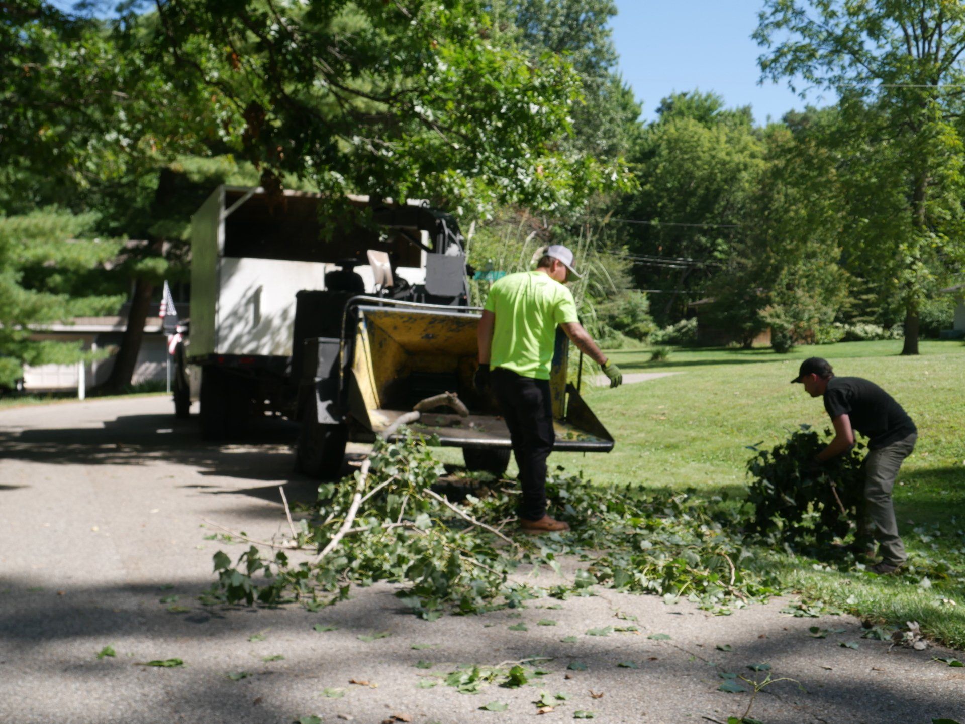 A man in a green shirt is standing next to a tree chipper