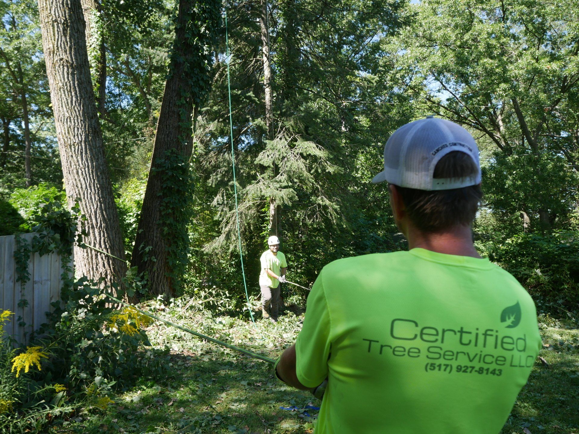 A man wearing a green shirt that says certified tree service