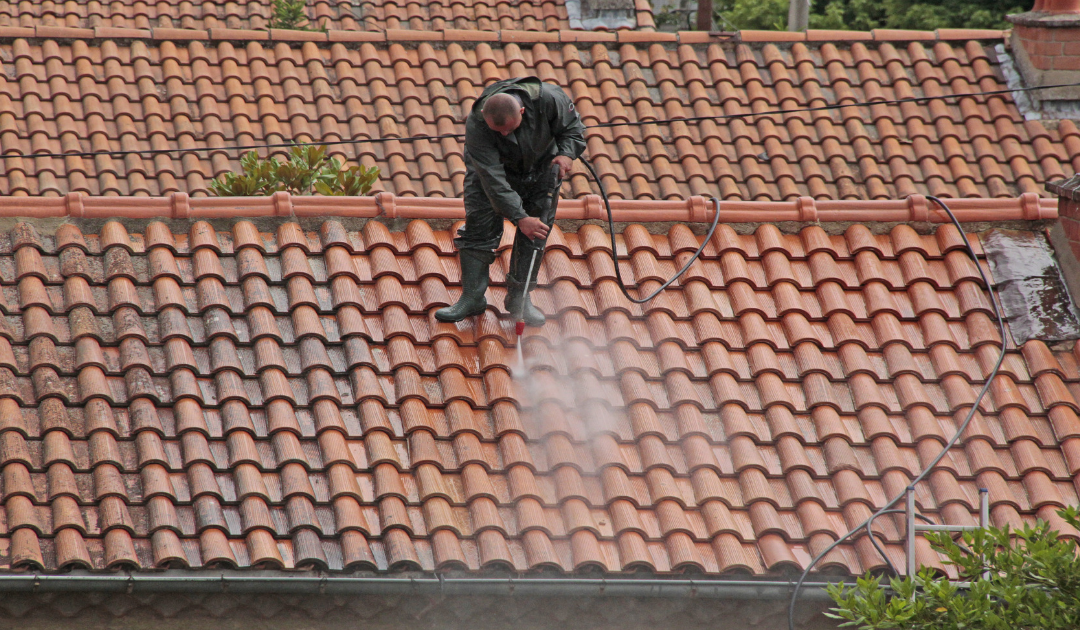 a man is cleaning a tiled roof with a high pressure washer MRI Roofing Roof Cleaning Melbourne