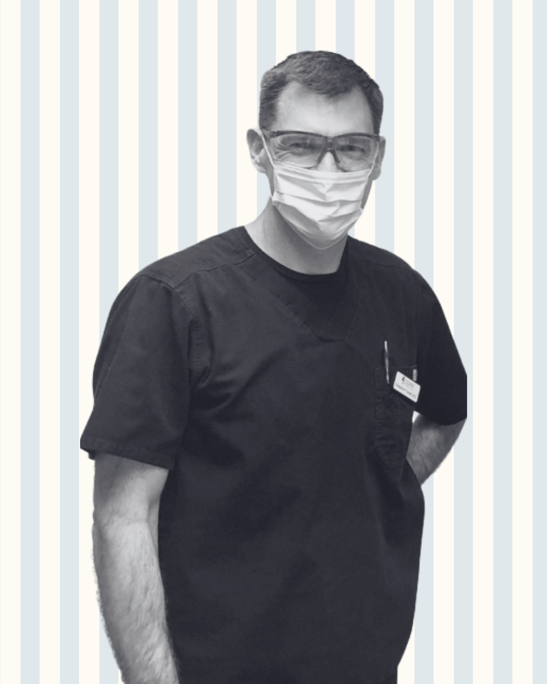 A man wearing a mask and glasses is standing in front of a striped background.