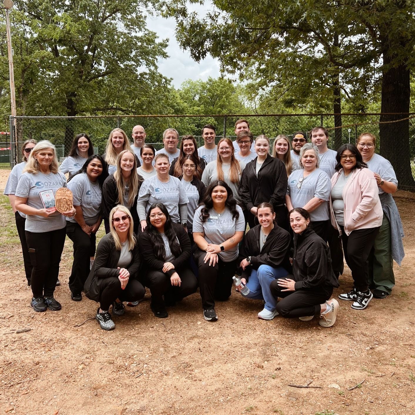 A large group of people are posing for a picture in a park.