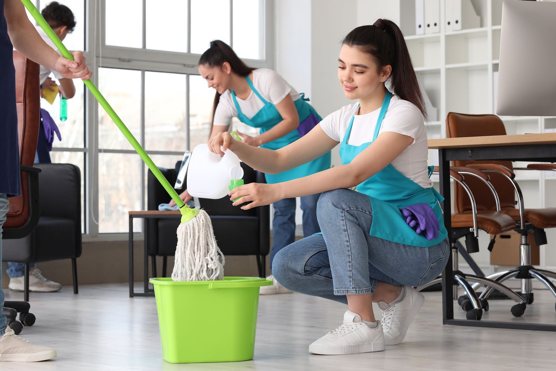 A group of cleaners are cleaning an office with mop and bucket.