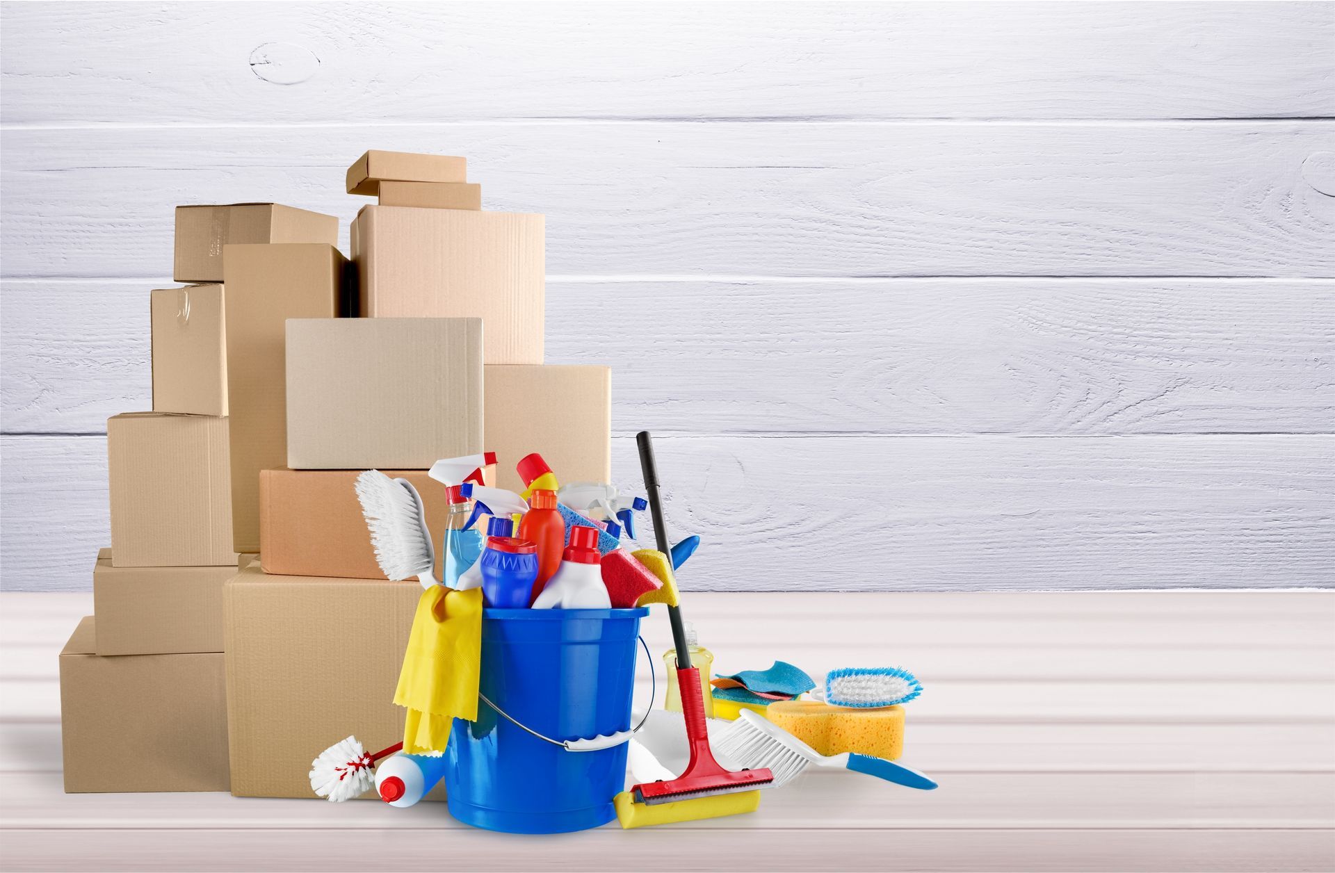 A pile of cardboard boxes and cleaning supplies on a wooden table.