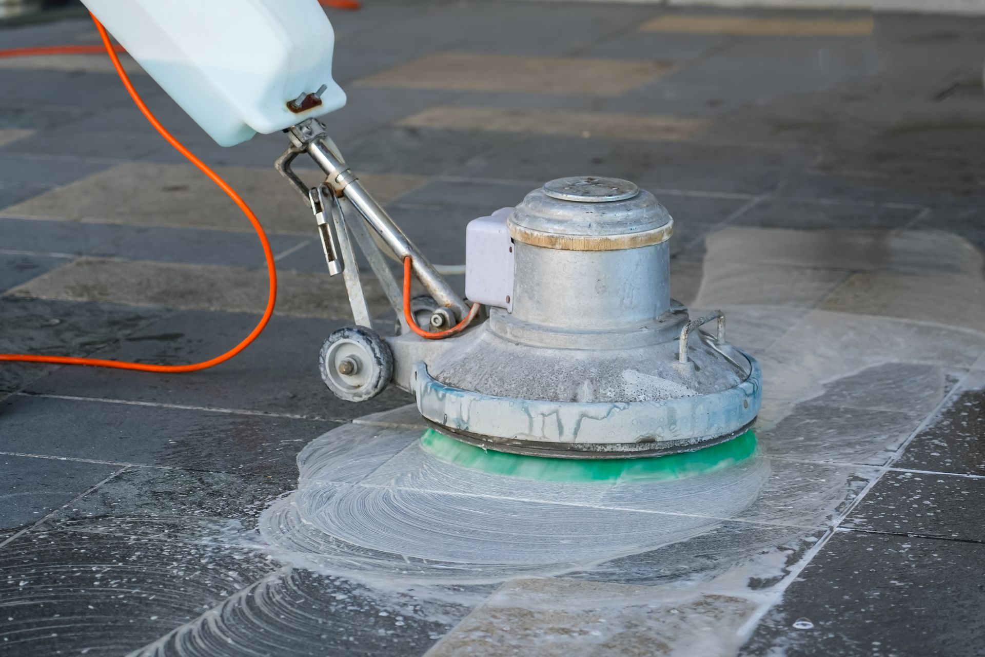 A man is cleaning a rug with a vacuum cleaner.