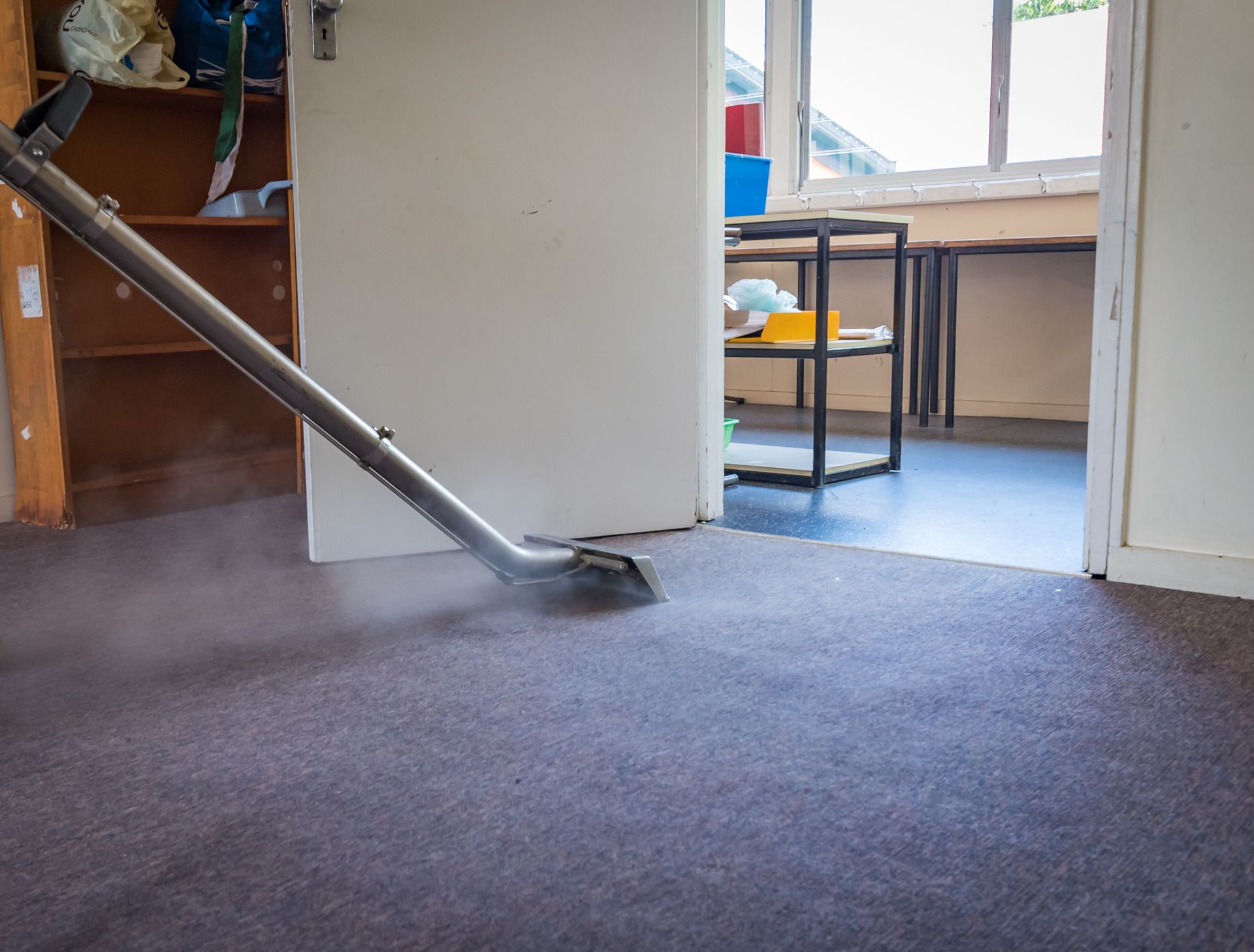 A man is cleaning a rug with a vacuum cleaner.
