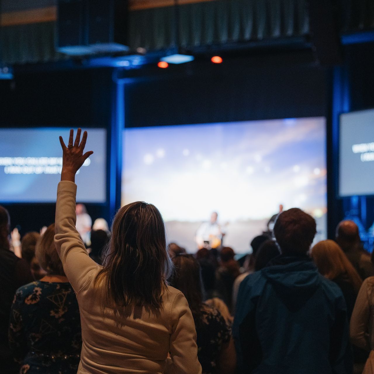 A woman is raising her hand in the air at a concert.