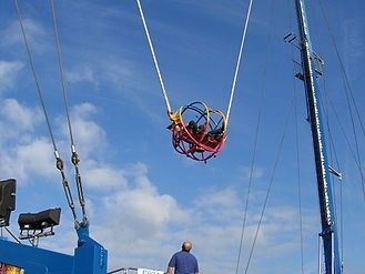 A man is standing next to a swing that is hanging from a crane.
