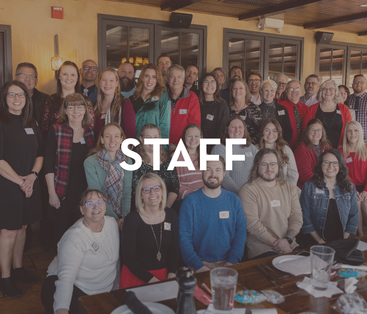 A large group of people are posing for a picture with the word staff above them