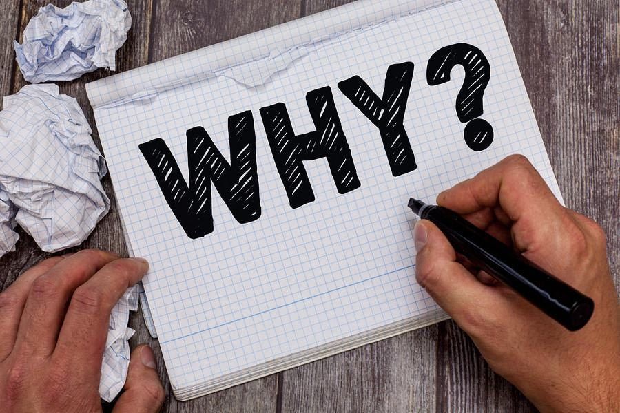 A person is writing the word why on a piece of paper.
