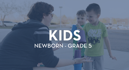 A man is talking to two young boys in a parking lot.