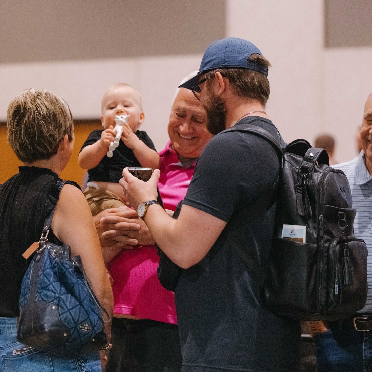 A man with a backpack is holding a baby in his arms