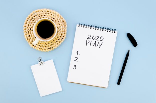 A notebook with the words `` 2020 plan '' written on it next to a cup of coffee and a pen.