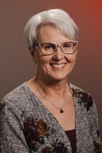 A man with a beard is smiling for the camera while wearing a green shirt.