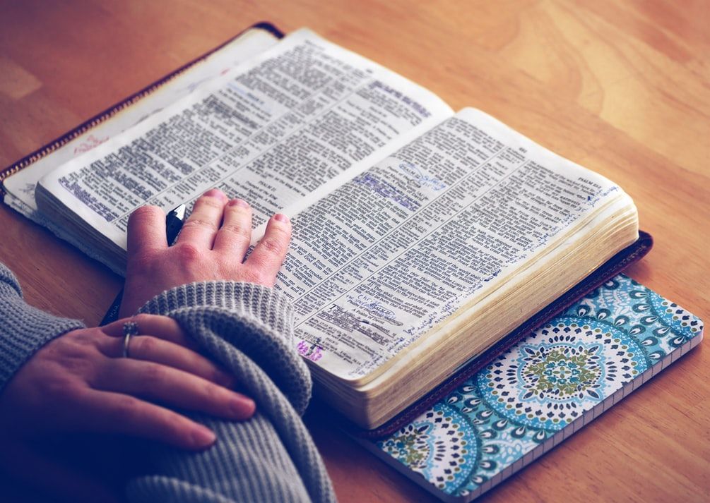 A person is sitting at a table reading a bible.