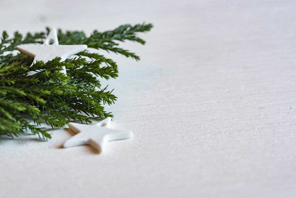A white star and a christmas tree branch on a white surface.