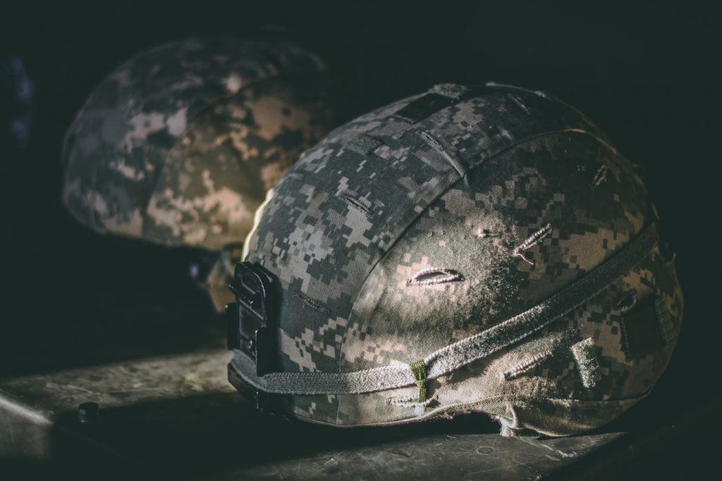 Two military helmets are sitting on top of each other on a table.