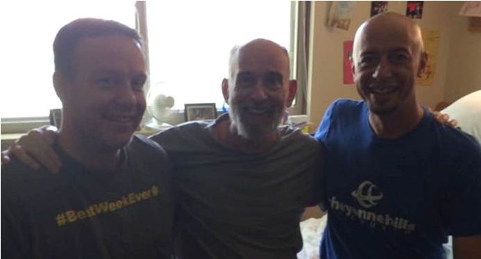 Three men are posing for a picture and one of them is wearing a shirt that says #begreenlives
