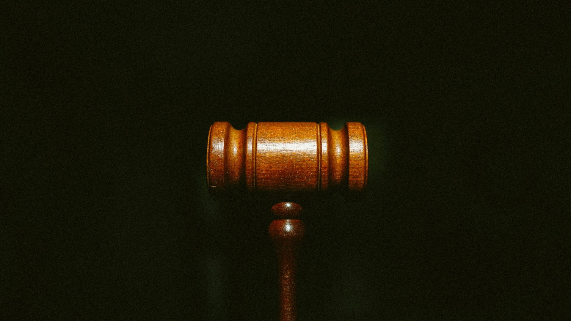 A wooden judge's gavel centered against a solid black background.