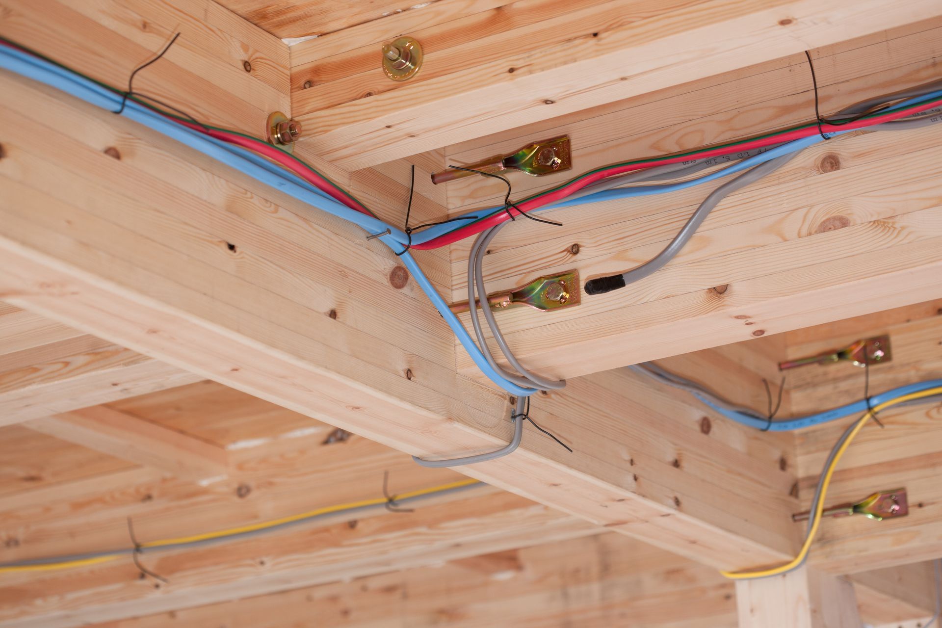 A bunch of wires are hanging from the ceiling of a wooden building.