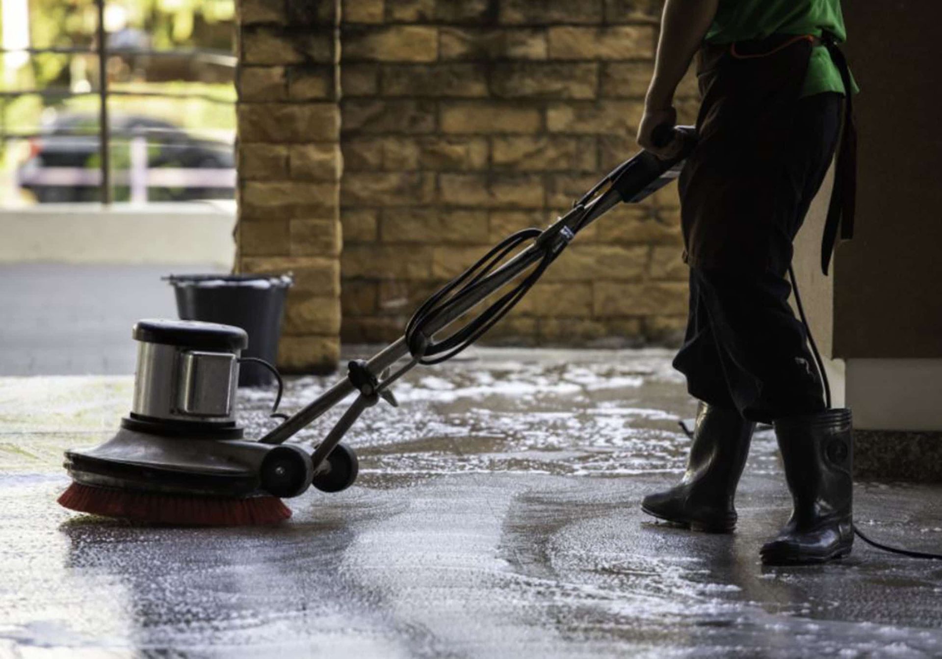 A person using a handheld vacuum cleaner to clean a mattress surface.