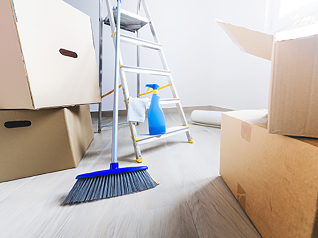 A person using a handheld vacuum cleaner to clean a mattress surface.