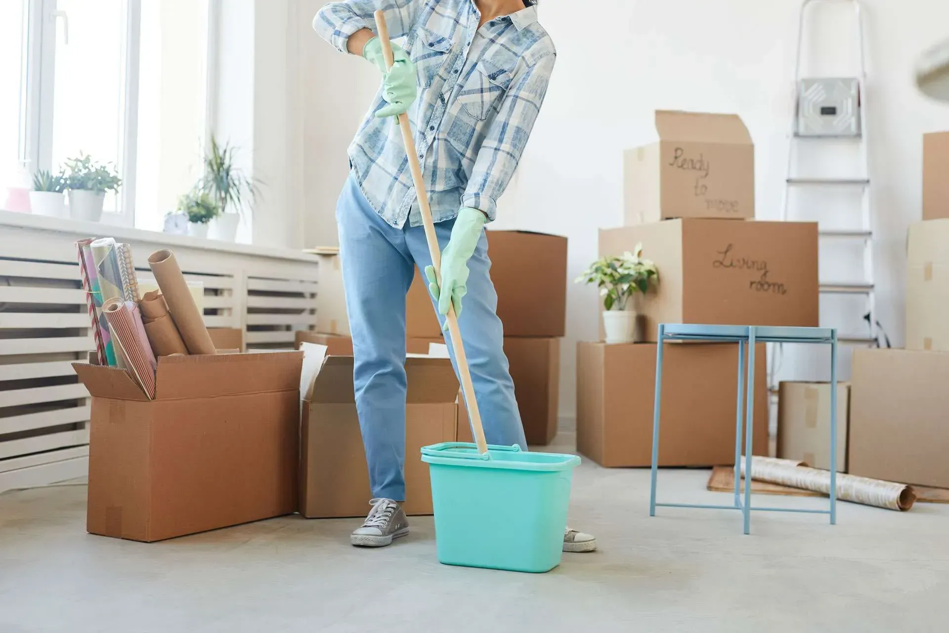 A person using a handheld vacuum cleaner to clean a mattress surface.