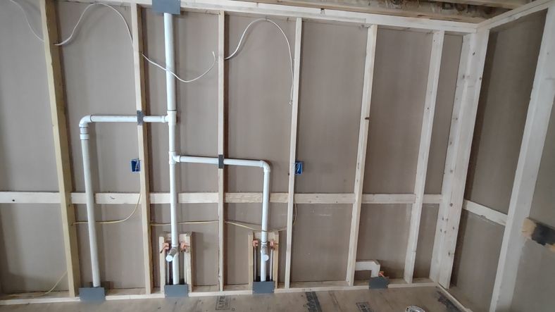 Rough-in plumbing wall showing side-by-side vanity drains.