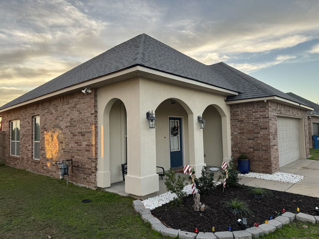 A brick house with a gray roof and arched porch.