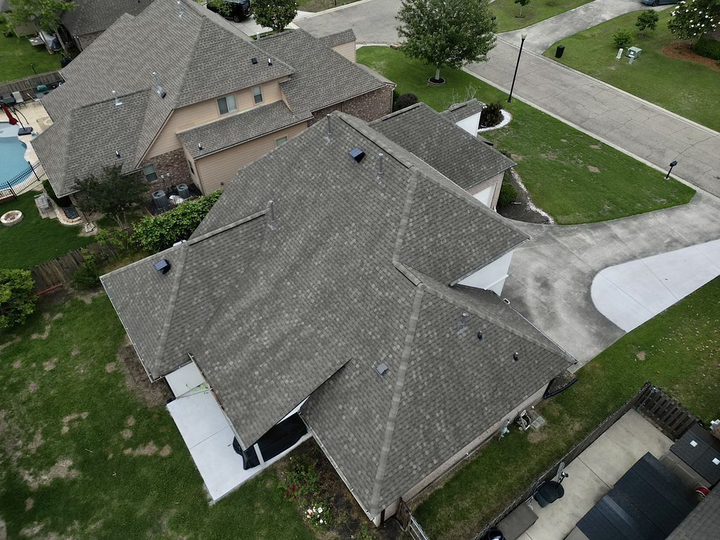 An aerial view of a house with a gray roof in a residential area.