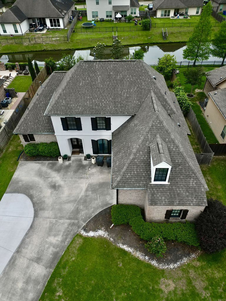 An aerial view of a large house with a gray roof in a residential area.