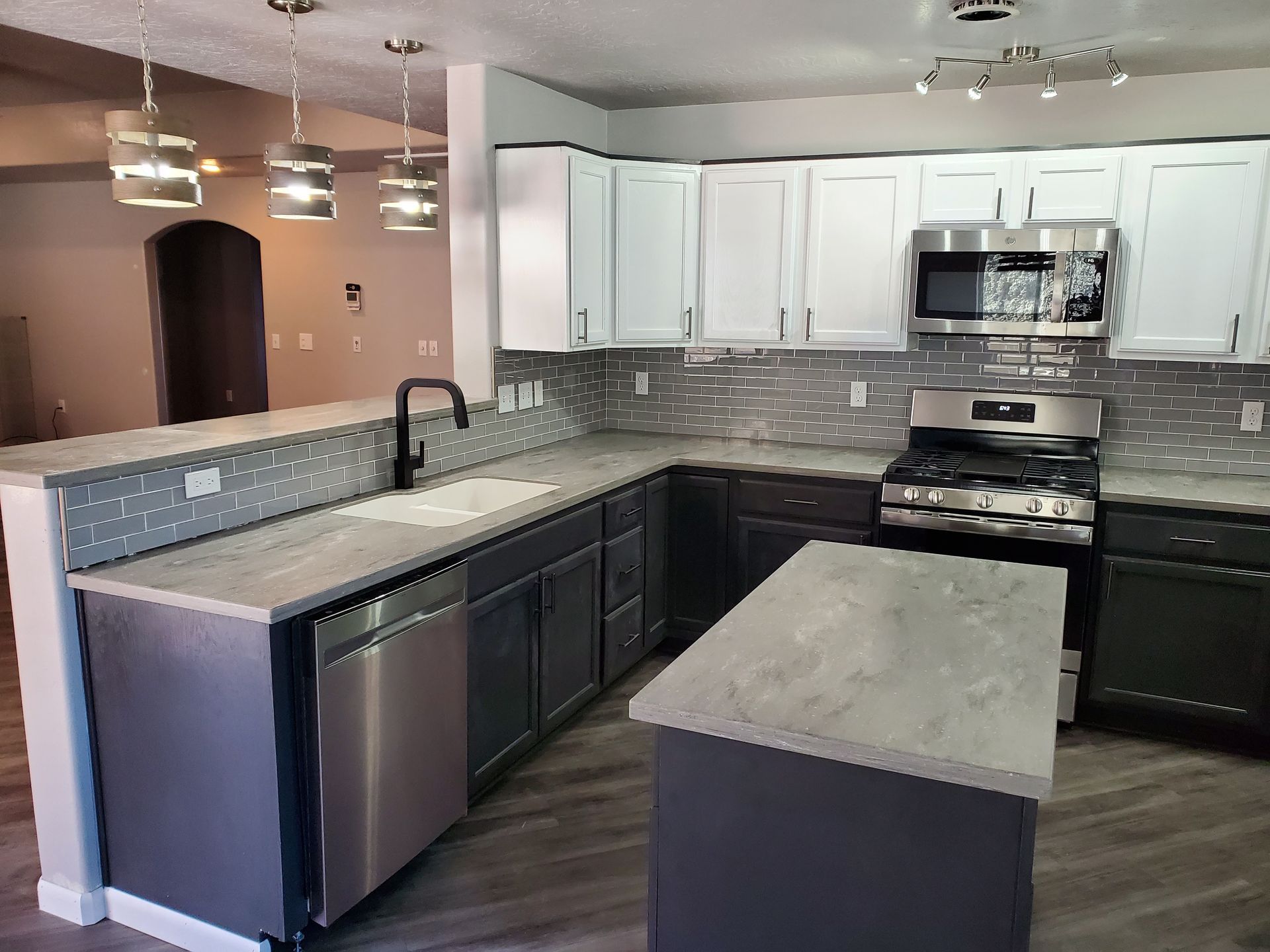 Modern kitchen with gray cabinets, island, and stainless steel appliances.