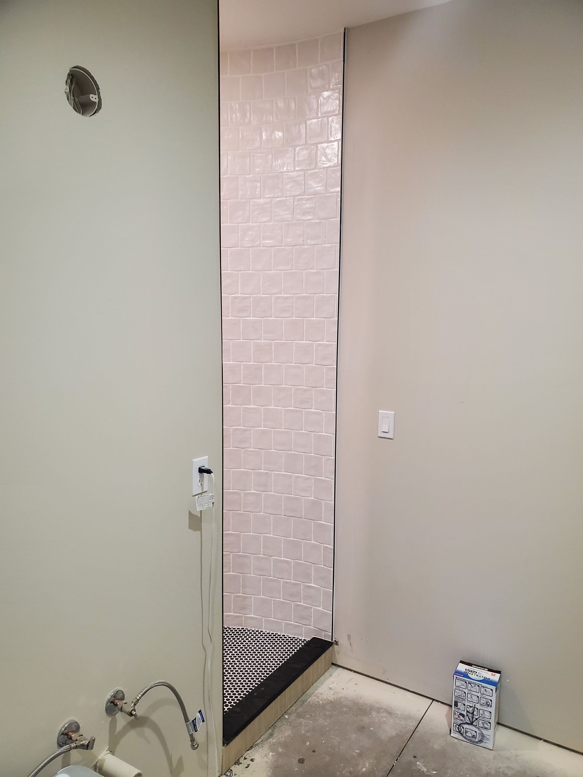 Bathroom with a narrow shower visible between walls; tiling in the shower and paint on surrounding walls.