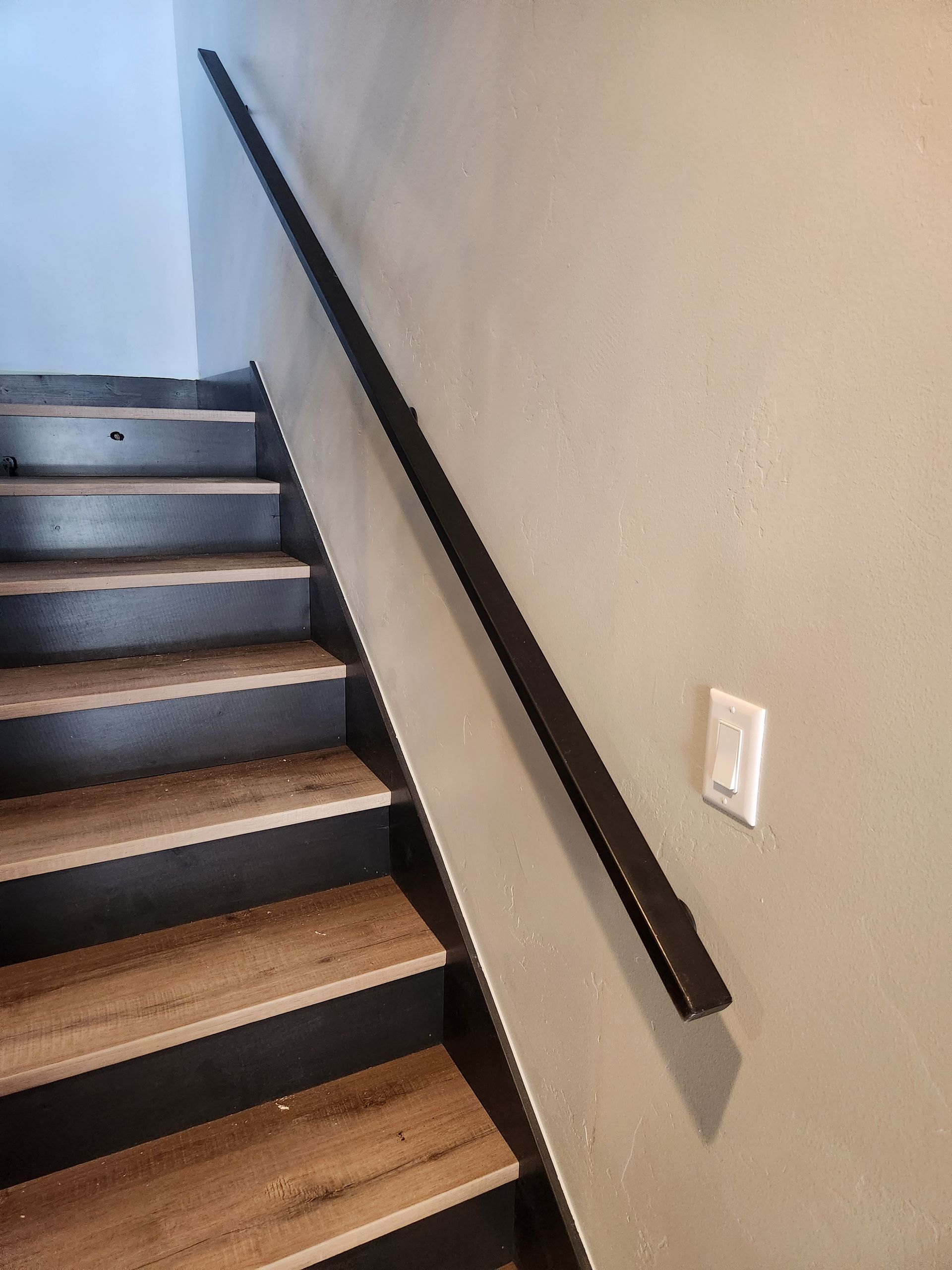 Roofer hammering a nail to secure a slate tile to a wooden roof frame, wearing a high-visibility vest.