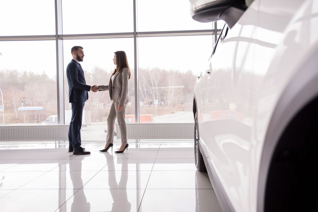 Un gruppo di persone guarda un'auto rossa in uno showroom