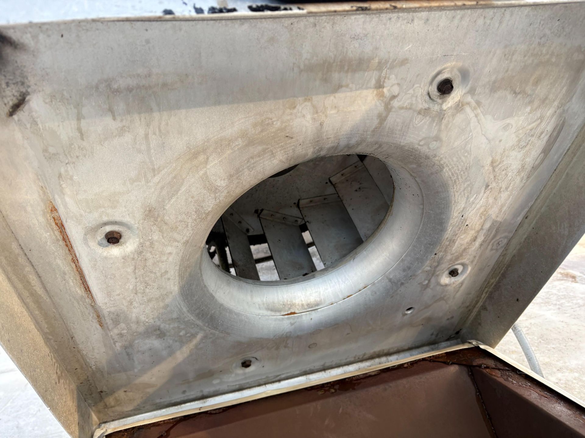 Inside view of a vintage metal oven with an oval air vent and square base.