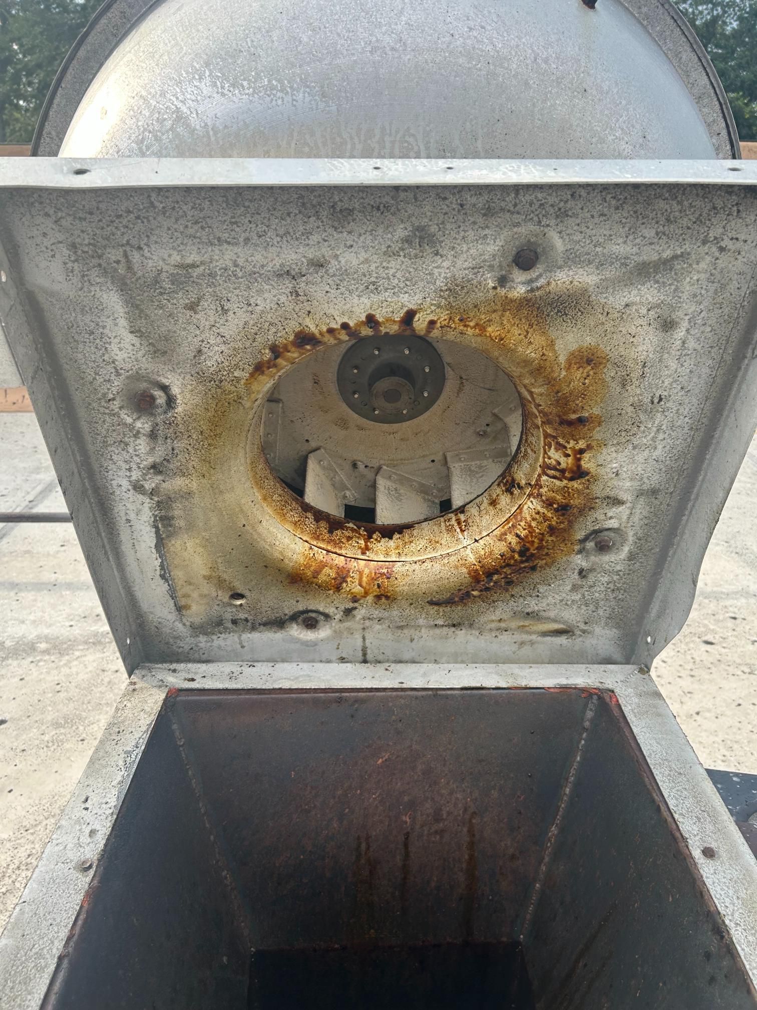 Open, rusty ventilation fan on a rooftop.
