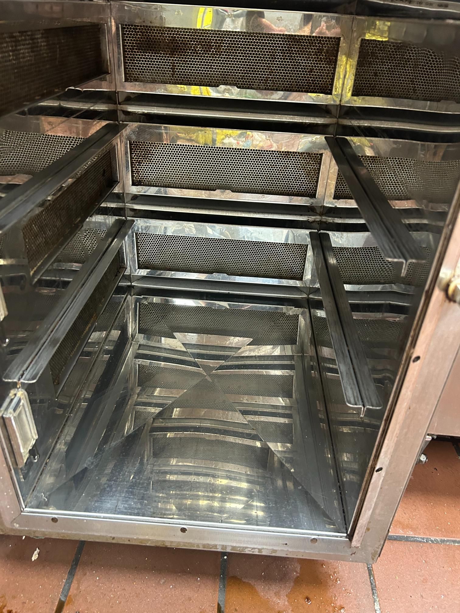 Inside of a stainless steel commercial warming oven, with racks and a metal mesh ceiling.