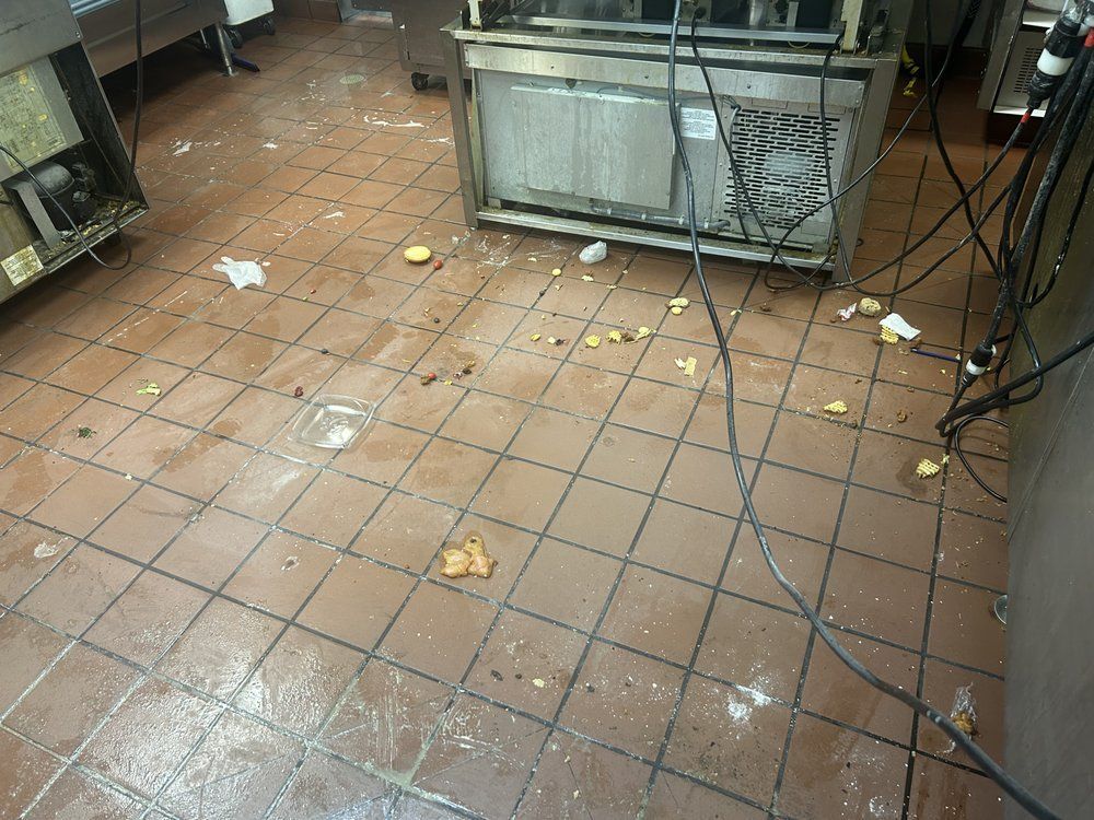 A dirty kitchen with a lot of trash on the floor.