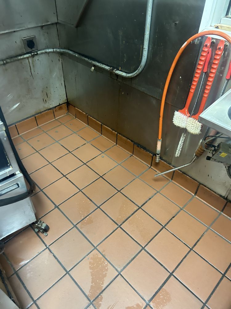 A tiled floor in a kitchen with a hose attached to it.