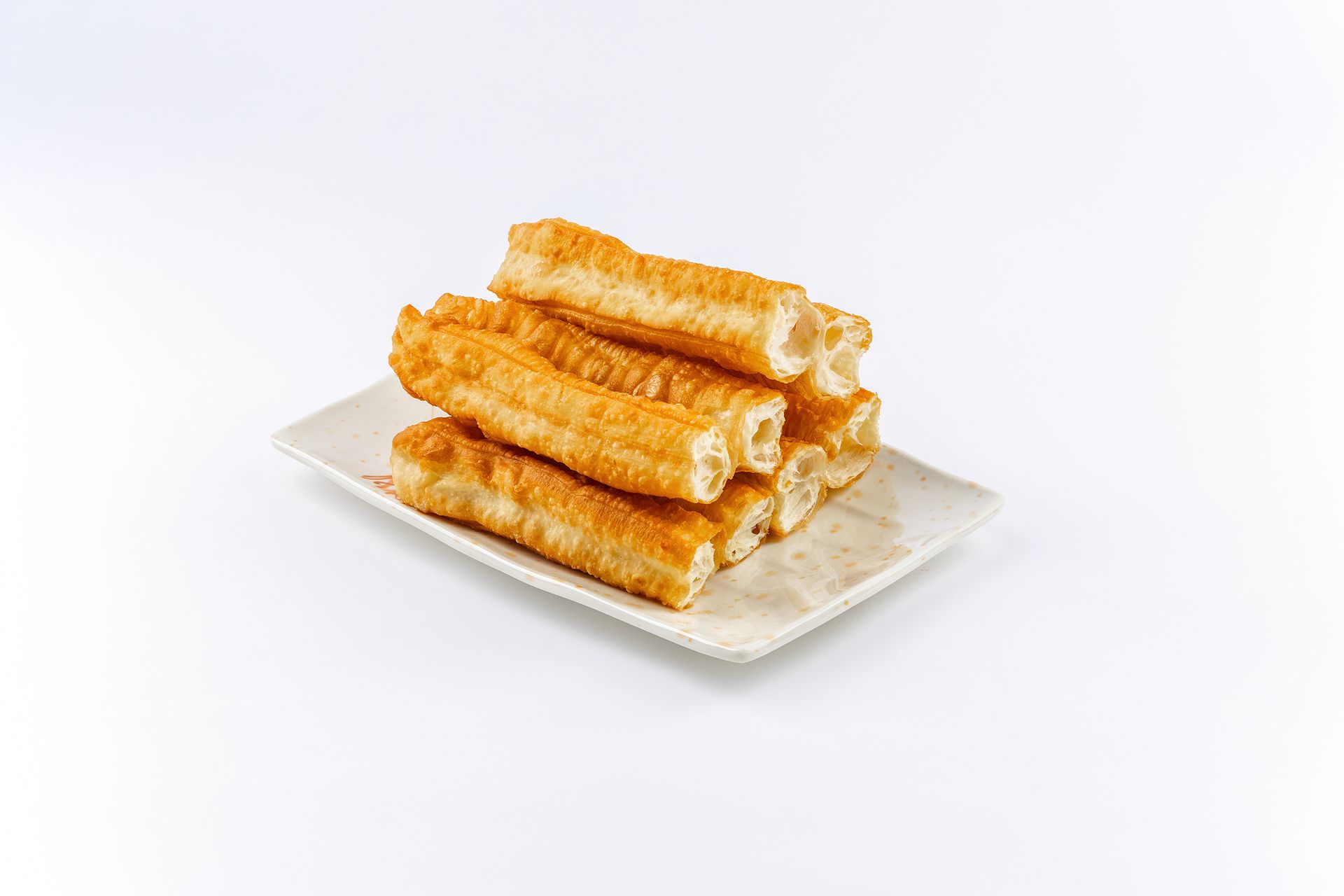 A stack of golden-brown Chinese fried dough sticks, or youtiao, served on a white rectangular plate.
